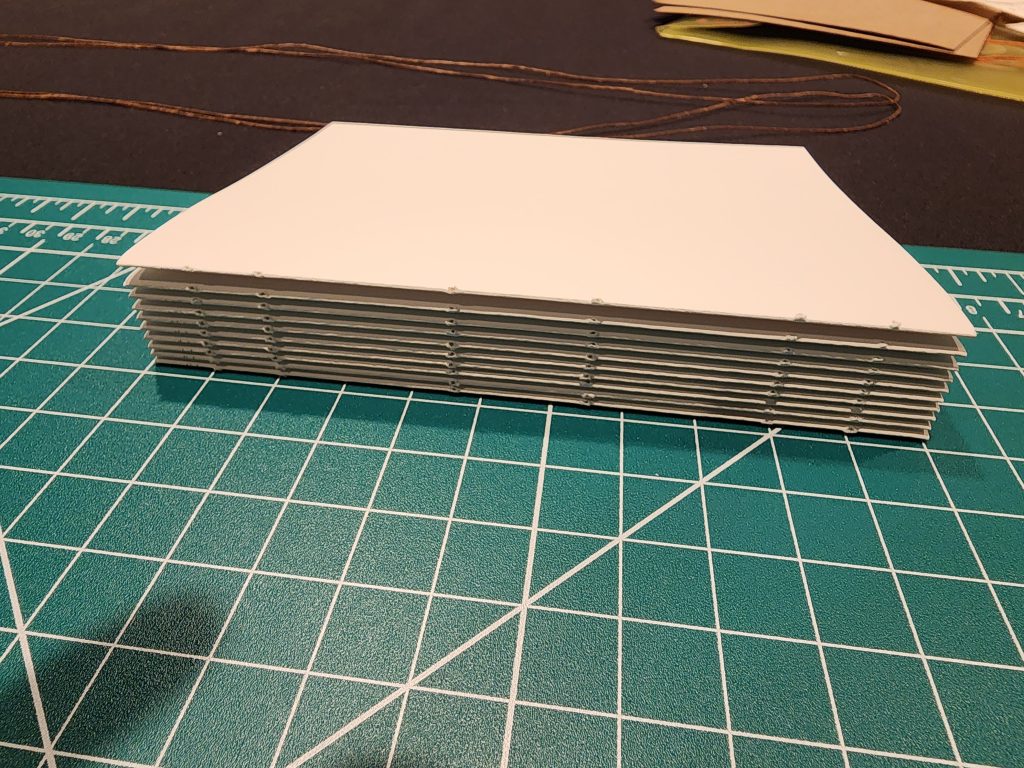A stack of folded pages, or sections, each punched and prepared for binding together.