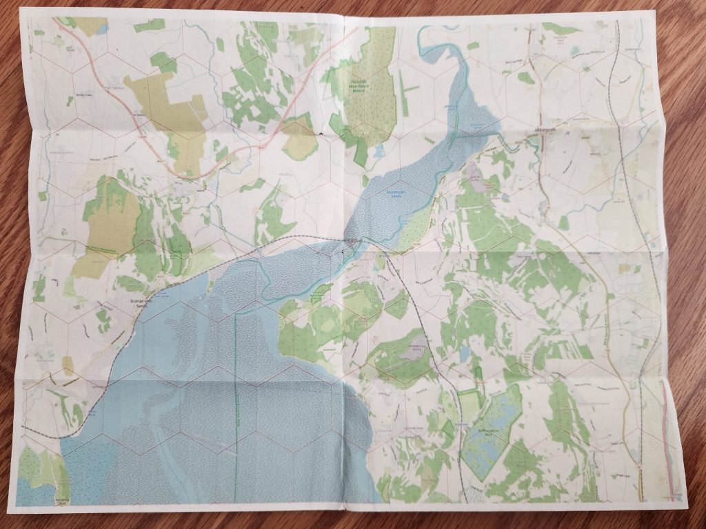 A sheet of paper, unfolded, depicting a map with various geographical features and overlaid with a hexagonal pattern.