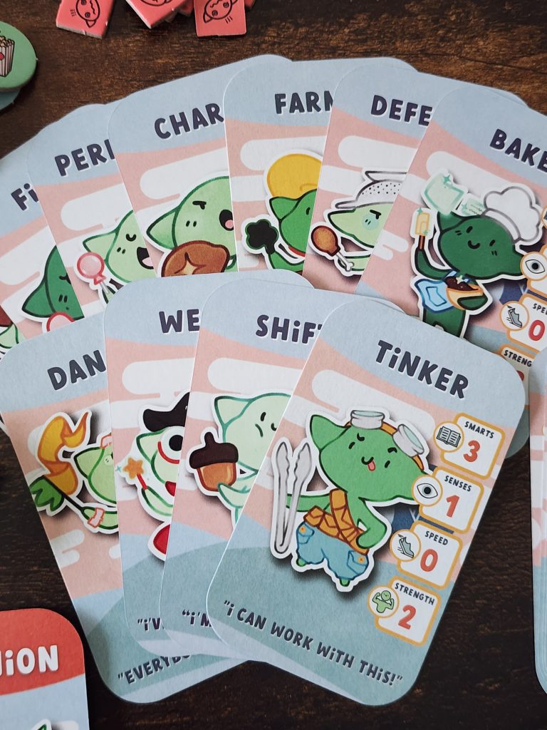 A closeup of the Adorablin character cards. Each card depicts a whimsical goblin with a specific job - Tinker, Baker, Defender, Farmer, and more. Each chard has a series of stats, including Smarts, Senses, Speed and Strength.