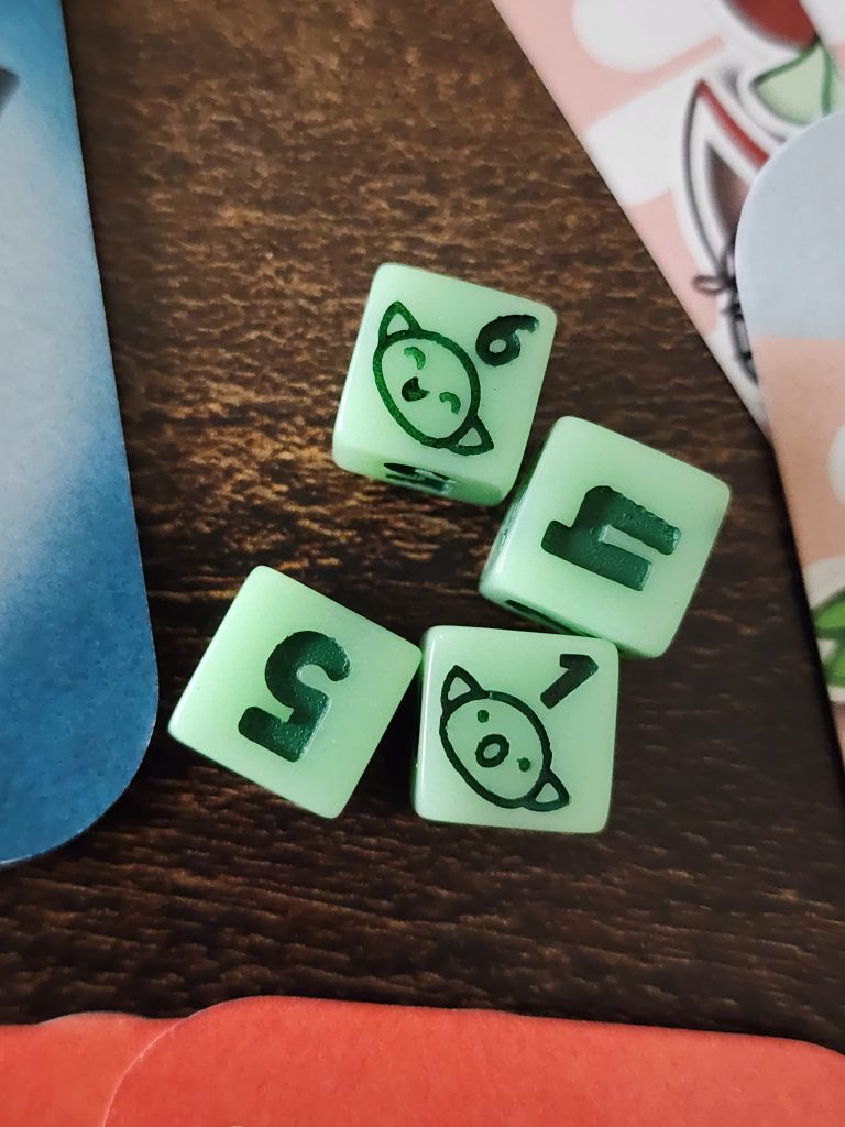 A zoomed in picture of a set of four, 8mm, 6-sided dice sitting on a tabletop. The dice are a light green colour, the inlaid numbers are a darker shade of green. On the 1's face is a depiction of a small goblin face, mouth agape as if it "failed" at something. On the 6's face is the depiction of a small goblin face, smiling and happy, as if successful in something.