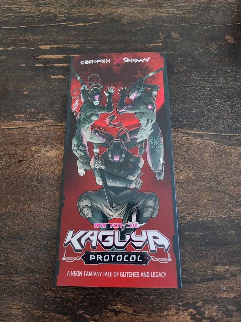 On a tabletop sits a folded pamphlet, mostly red and black, reading CBR+PNK x Onigami, Kaguya Protocol. An adventure crossover for the CBR+PNK, inspired by a new RPG system, Onigami. The cover of the pamphlet depicts 3 ninja-inspired characters, outfit with swords, high-tech bodies, and cybernetic equipment.