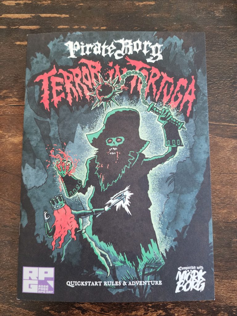 An a5 sized printed zine sits on a tabletop. The cover reads "Pirate Borg Terror in Tortuga", a Mork Borg compatible quick start and adventure. It depicts a large zombified sea captain, with its large hat, wielding a flail overhead and a heart grasped in its offhand. In front of it, a person with long, red hair swings an axe into its body.
