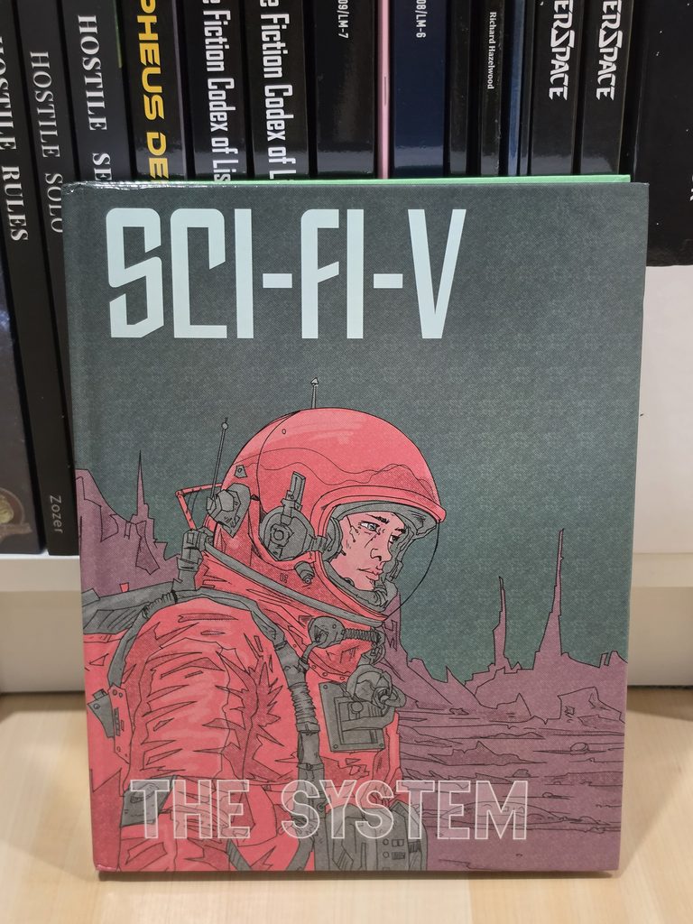 A hardbound TTRPG book is propped against a bookshelf. The book title, "Sci-Fi-V: The System". The cover depicts an astronaut suited up, with an alien landscape behind them. There is a variety of other science fiction RPG books partially visible behind it.